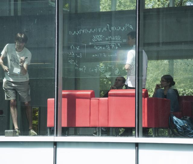 researchers interacting behind a window at PI