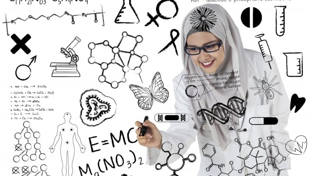 Young woman writing equations on glass with black marker